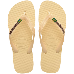 light yellow flip flops with yellow straps that say havaianas in brown, and a brazil flag, top view